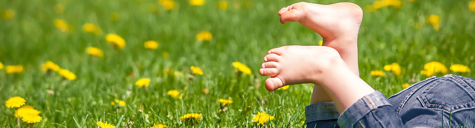 Kind liegt barfuß auf Blumenwiese